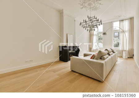 a living room with white walls and hardwood flooring the room is well lit by the light from the windows a living room with white walls and hardwood flooring the room is well lit by the light from the windows 108155360