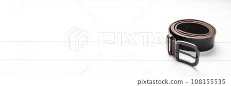twisted brown leather belt on wooden background 108155535