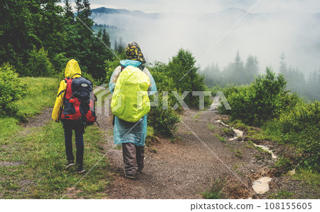 Two tourists in raincoat hike to mountain in the fog 108155605