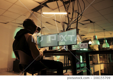 Male hacker working to hack server with vr 3d headset, planning cyberattack with virtual reality at night. Young adult causng computer malware, using interactive glasses, cyberterrorism. 108155709