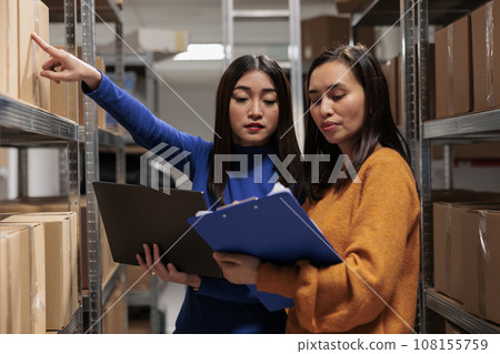 Warehouse worker and supply chain manager tracking inventory in storage room. Storehouse employees planning parcel stocking process optimization, analyzing orders checklist on clipboard Warehouse worker and supply chain manager tracking inventory in storage room. Storehouse employees planning parcel stocking process optimization, analyzing orders checklist on clipboard 108155759