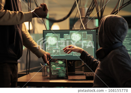 Angry hackers failing to hack computer system online, using monitors and tablet late at night. Unsuccessful password cracking, trying to access server for cyberattack, stealing data. 108155778