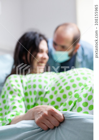 Husband comforting pregnant woman during child birth in hospital ward, future mother screaming and pushing during caesarean surgery. Patient with pregnancy getting into labor in maternity clinic 108155965