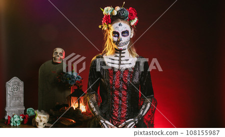 Spooky goddess of death with skull make up and horror costume to celebrate dios de los muertos on mexican halloween. Creepy woman dressed as santa muerte on day of the dead holiday. Spooky goddess of death with skull make up and horror costume to celebrate dios de los muertos on mexican halloween. Creepy woman dressed as santa muerte on day of the dead holiday. 108155987