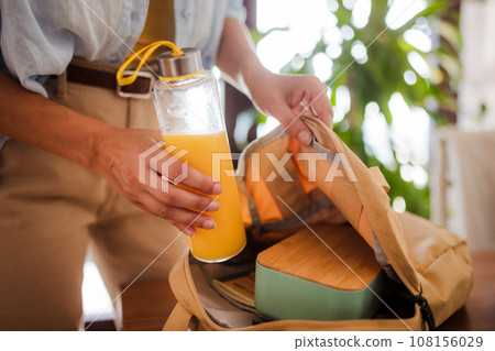 Mother packing school bottle of juice, snacks for her children into school bag. Snack, school lunch in a snack box for school. Mother packing school bottle of juice, snacks for her children into school bag. Snack, school lunch in a snack box for school. 108156029