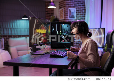Gamer girl ecstatic after killing opponents in online multiplayer shooting game and winning competition. Woman at computer desk releasing pent up emotions, doing victorious yelling 108156264