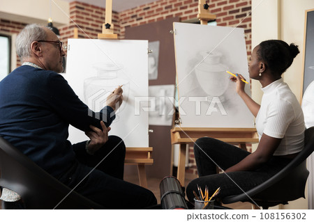 Diverse different aged people students talking during drawing class, senior man and young woman communicating during art course, improving sketching skill. Creative hobbies for adults 108156302