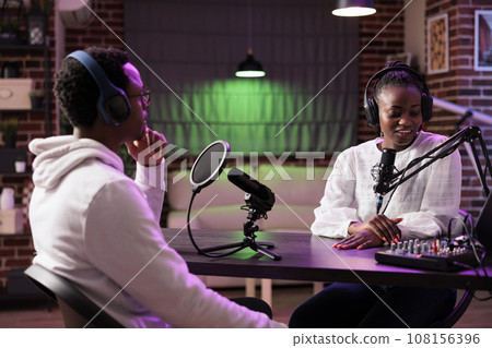 Online show host interviewing celebrity guest during live broadcast for streaming service website, talking about her life. Internet talking show interviewer using professional tools to record podcast Online show host interviewing celebrity guest during live broadcast for streaming service website, talking about her life. Internet talking show interviewer using professional tools to record podcast 108156396
