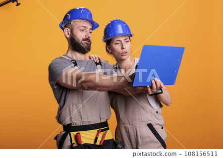 Team of renovators analyzing papers on clipboard, taking notes of construction measurements. Builders looking at files with building or renovating information, engineering skills. 108156511
