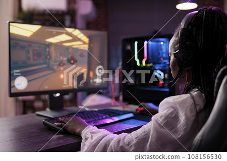 Content creator playing online multiplayer videogame at computer station, competing in live esports tournament. African american woman streaming game for fans watching from home 108156530