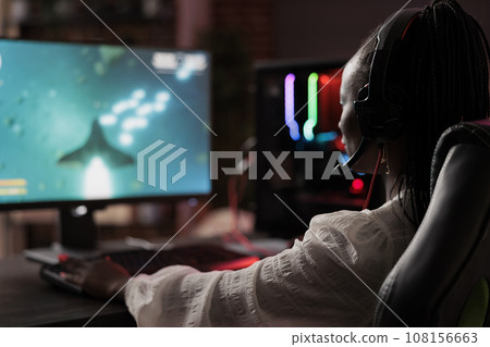 Frustrated gamer losing online multiplayer spaceship arcade racing videogame, being defeated by more powerful opponents. African american woman unable to keep up with more skillful players Frustrated gamer losing online multiplayer spaceship arcade racing videogame, being defeated by more powerful opponents. African american woman unable to keep up with more skillful players 108156663