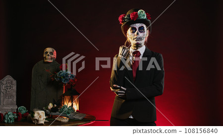 Creepy model in costume with skull make up celebrating mexican halloween, looking like lady of death. La cavalera catrina holy culture celebration with black and white body art. 108156840