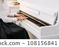Beautiful woman dressed in white dress playing on white piano 108156841