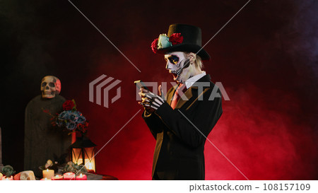 Horror female model browsing internet website on smartphone, wearing suit and hat to celebrate day of the dead. Lady of death surfing online on mobile phone, social media. Handheld shot. Horror female model browsing internet website on smartphone, wearing suit and hat to celebrate day of the dead. Lady of death surfing online on mobile phone, social media. Handheld shot. 108157109