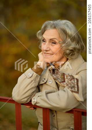 Senior woman walking in the park in autumn. Senior woman walking in the park in autumn. 108157405