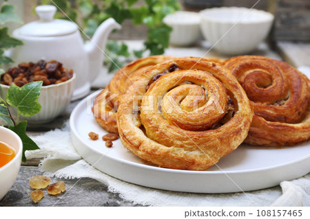 French roll raisin buns, teapot and cup of tea for sweet breakfast 108157465