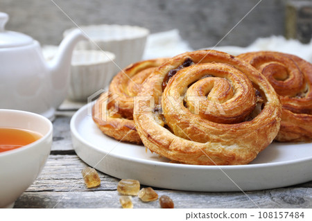 French roll raisin buns, teapot and cup of tea for sweet breakfast 108157484
