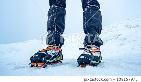 Man wearing crampons standing on snow 108157973