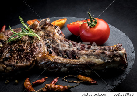 Beef steak with rosemary, chili peeper and tomatoes on slate board Beef steak with rosemary, chili peeper and tomatoes on slate board 108158056