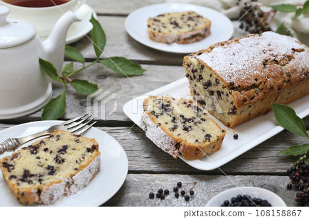 Summer baking. Black elderberry cake, teapot and cup of tea for summer tea party Summer baking. Black elderberry cake, teapot and cup of tea for summer tea party 108158867