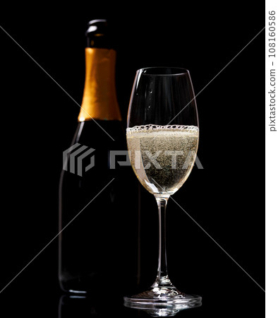 Champagne glass and bottle on a black Champagne glass and bottle on a black 108160586