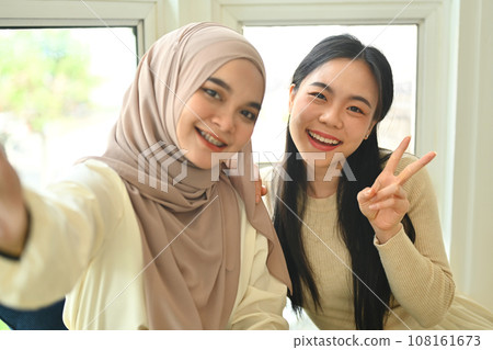 Cheerful female friends taking selfie with smartphone for post on blog or social media 108161673