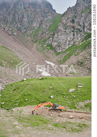 Excavator works in the highlands. Clears the consequences of a mudslide in the gorge of the mountains. repair and expansion of a road 108161690