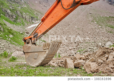 Excavator works in the highlands. Clears the consequences of a mudslide in the gorge of the mountains. repair and expansion of a road Excavator works in the highlands. Clears the consequences of a mudslide in the gorge of the mountains. repair and expansion of a road 108161696