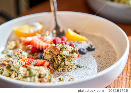 Chia pudding with homemade coconut granola, peanut butter and berries in gray bowl. Healthy plant based diet, detox, summer recipe. Breakfast in the Restaurant. 108161736