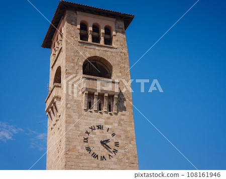 Travel to Greece, Mediterranean islands Rhodes. medieval tower clock, arched windows and doors and stone square on Rhodes island 108161946