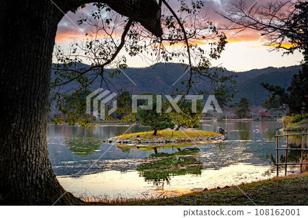 Autumn at Daikakuji Monzeki, with Arashiyama in the background, Osawa Pond with its autumn leaves at its peak, Kikugashima and the evening light enveloping the stones of the garden lake. 108162001