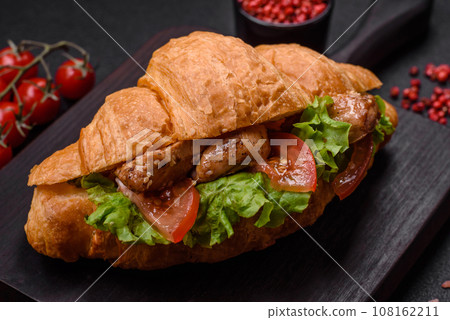 Delicious fresh crispy croissant with chicken or beef meat, lettuce, tomatoes, spices and sauce Delicious fresh crispy croissant with chicken or beef meat, lettuce, tomatoes, spices and sauce 108162211