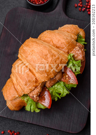 Delicious fresh crispy croissant with chicken or beef meat, lettuce, tomatoes, spices and sauce Delicious fresh crispy croissant with chicken or beef meat, lettuce, tomatoes, spices and sauce 108162213