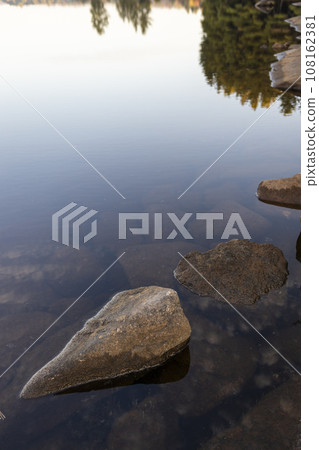 Reflection of waterside rocks and autumn leaves 108162381