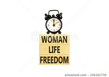 Woman life freedom symbol. Concept words Woman Life Freedom on wooden blocks on a beautiful white table white background. Black alarm clock. Social issue woman life freedom concept. Copy space. 108162730