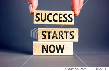 Success starts now symbol. Concept word Success starts now on beautiful wooden block. Businessman hand. Beautiful grey table background. Business motivational success starts now concept. Copy space. 108162731