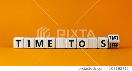 Time to sleep or start symbol. Turned a wooden cube and changed words 'time to sleep' to 'time to start'. Beautiful orange background. Business and time to sleep or start concept, copy space. 108162811