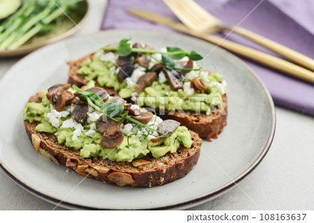 Avocado toast  with mushrooms, feta cheese and microgreens 108163637