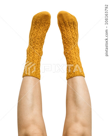Female legs in yellow hand knitted wool socks 108163792