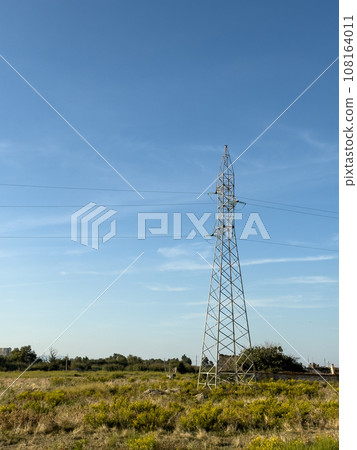 Overhead line pylons, high voltage pylons in meadow with mountains on background Overhead line pylons, high voltage pylons in meadow with mountains on background 108164011