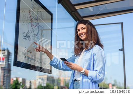 Young stylish woman waiting for public transport while standing at the modern tram station outdoors Young stylish woman waiting for public transport while standing at the modern tram station outdoors 108164938