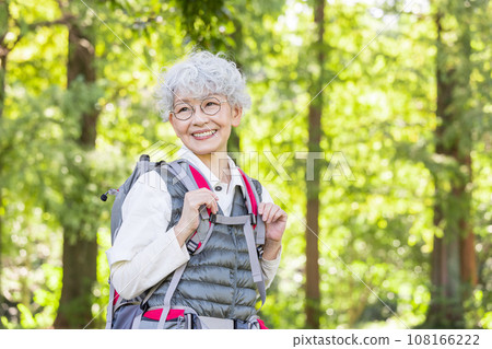 一位快樂的老年人徒步穿越新鮮的綠色植物 108166222