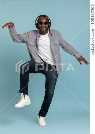 Positive bearded dark skinned man in headphones dancing making movements to music. 108167309