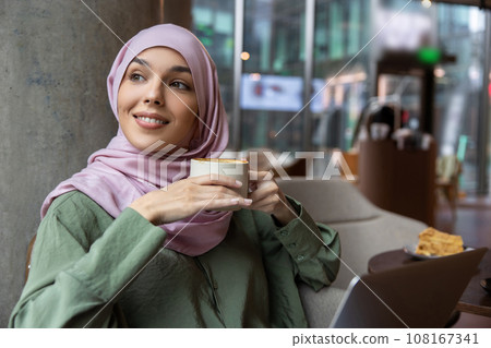 Cute woman in hijab sitting in a cafe and smiling 108167341