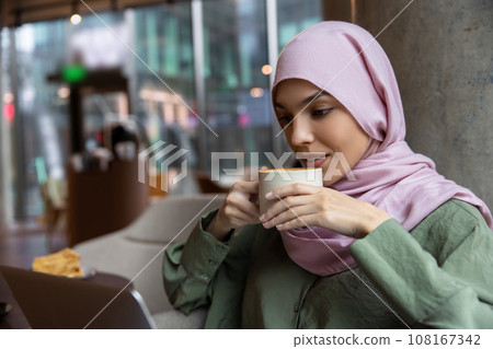 Cute woman in hijab sitting in a cafe and smiling Cute woman in hijab sitting in a cafe and smiling 108167342