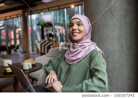 Cute woman in hijab sitting in a cafe and smiling Cute woman in hijab sitting in a cafe and smiling 108167343