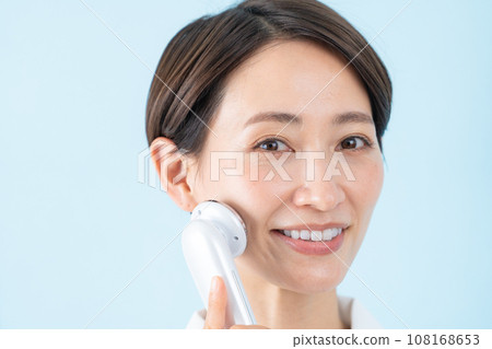 Middle-aged woman using facial beauty device 108168653