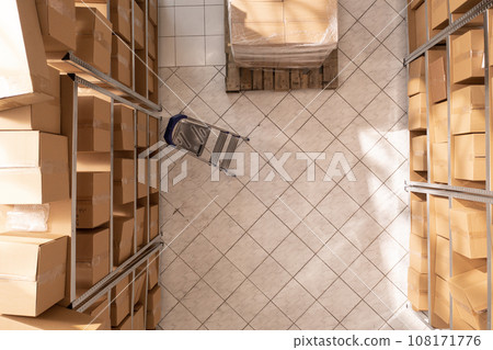 Empty storehouse full with metallic shelves and cardboard boxes, waiting for employee to come and work at customers orders. Storage room with nobody in it ready for packages delivery Empty storehouse full with metallic shelves and cardboard boxes, waiting for employee to come and work at customers orders. Storage room with nobody in it ready for packages delivery 108171776