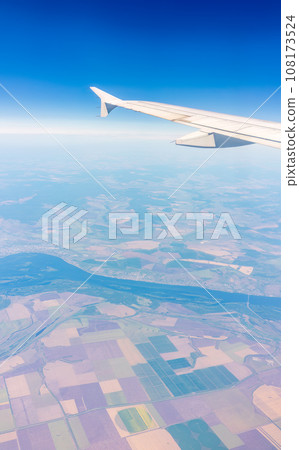Aerial view from airplane window above green ground. View from the airplane window with beautiful clouds at sunrise 108173524