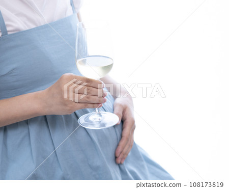 拿著裝滿白酒的酒杯的孕婦 拿著裝滿白酒的酒杯的孕婦 108173819